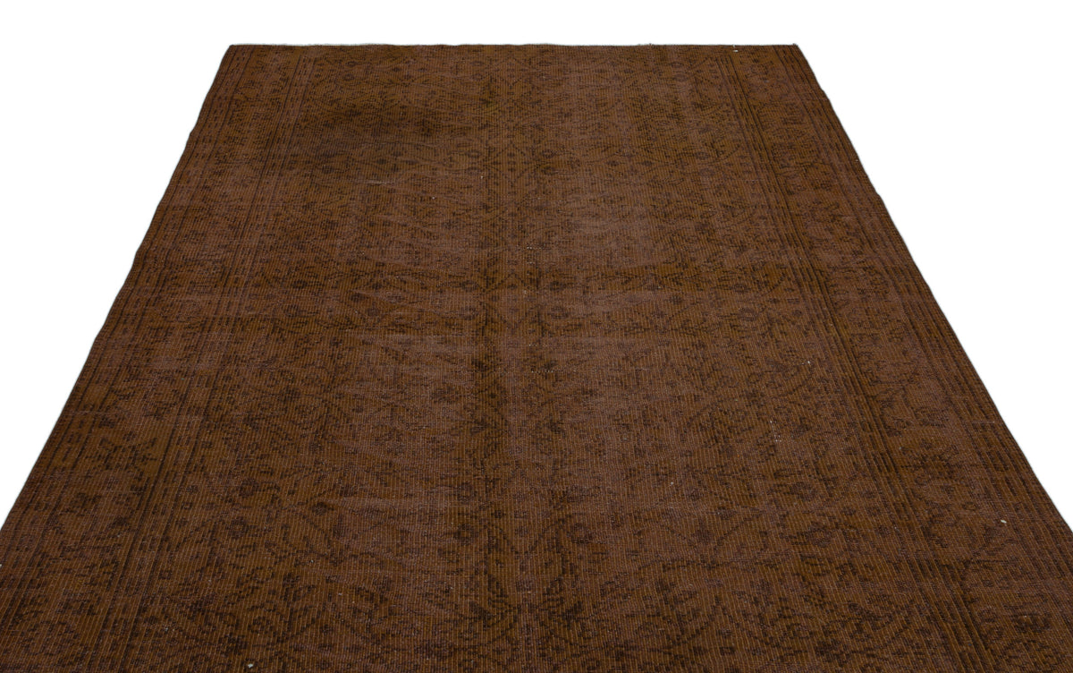 Dark brown monochromatic rug with a subtle, distressed floral medallion pattern and a bordered edge.