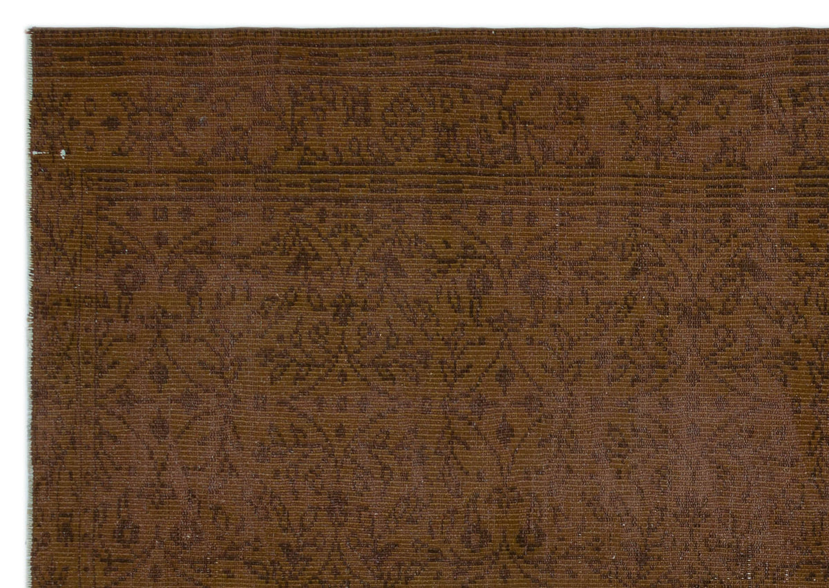 Dark brown rug with a tonal, low-contrast floral medallion pattern and a linear border.