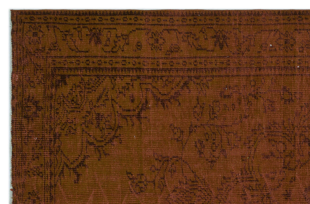 Rust-colored rug with a dark brown traditional floral border and intricate botanical pattern.