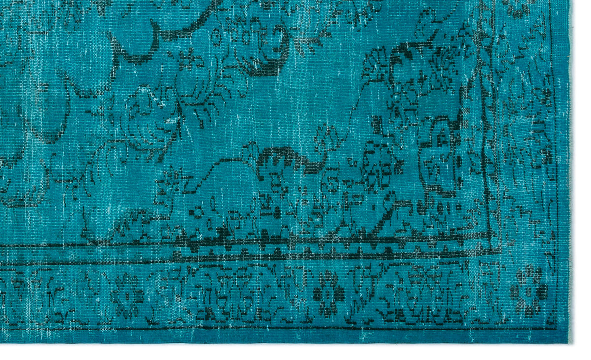 Teal rug with a distressed black traditional floral medallion pattern and a geometric border.