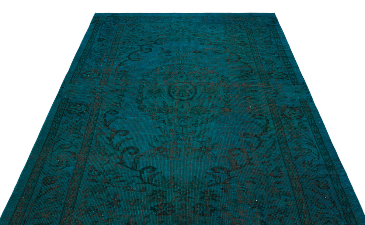 Teal rug with a dark, distressed traditional floral medallion pattern on a white background.