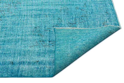 Load image 1 in gallery view. Bright turquoise rug with a distressed, faded pattern and a folded corner showing the woven backing.