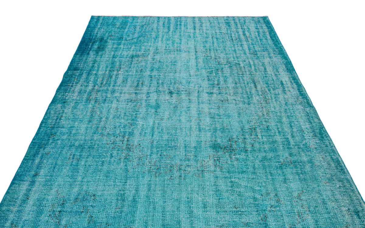 Teal distressed vintage-style rug with a faded, overdyed pattern on a white background.
