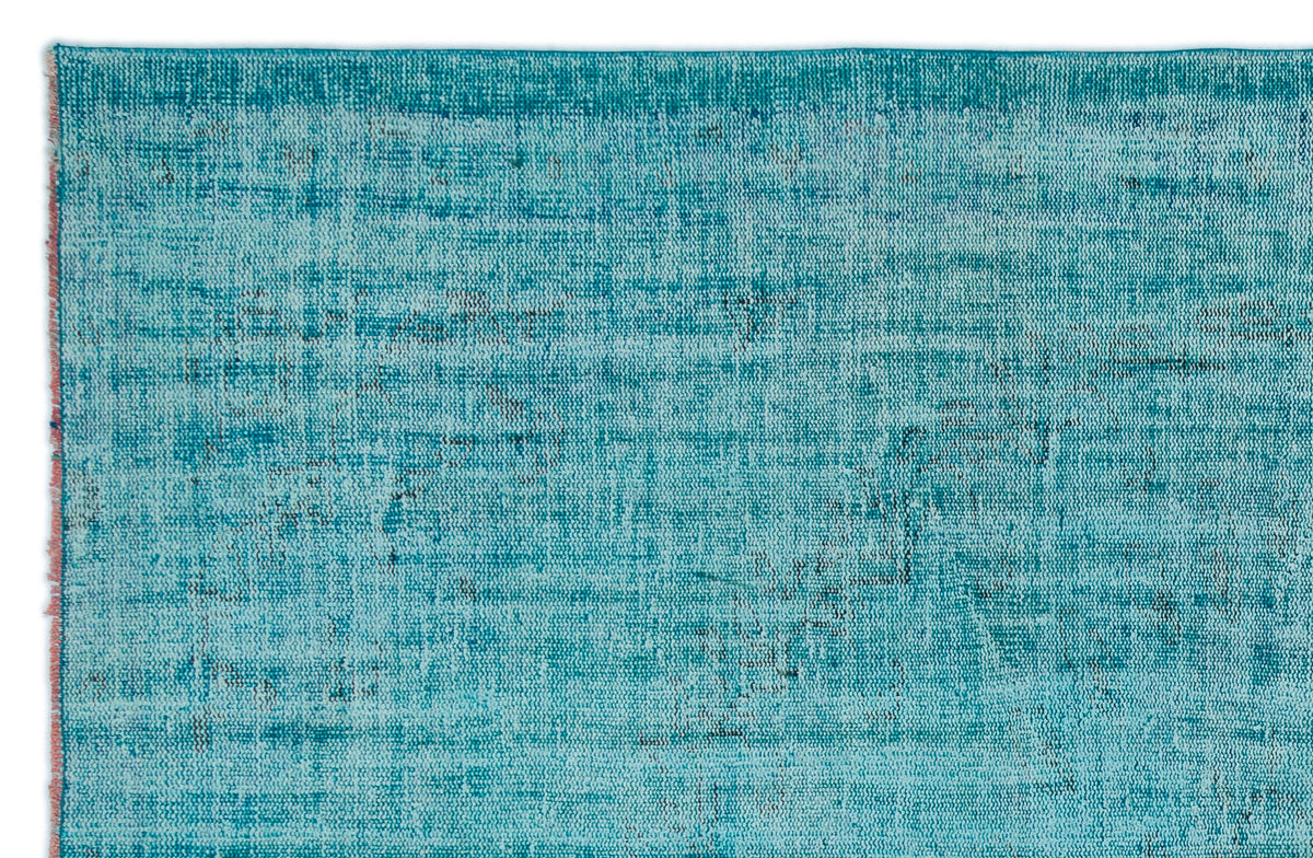 Teal and turquoise distressed rug with a faded, textured pattern and a frayed edge.