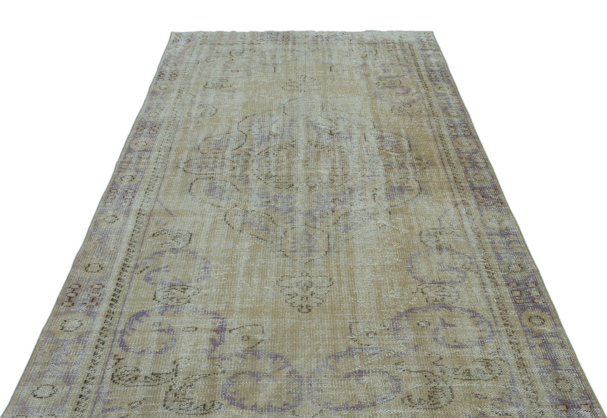Distressed beige and lavender vintage-style rug with a central medallion and ornate border pattern on a white background.