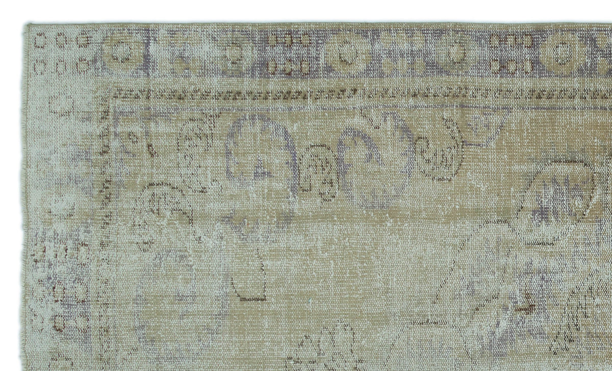 Beige and muted purple distressed rug with a faded traditional floral medallion pattern and geometric border.