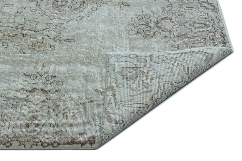 Load image 1 in gallery view. Light gray and brown distressed rug with a faded floral medallion pattern, shown with a corner folded over.