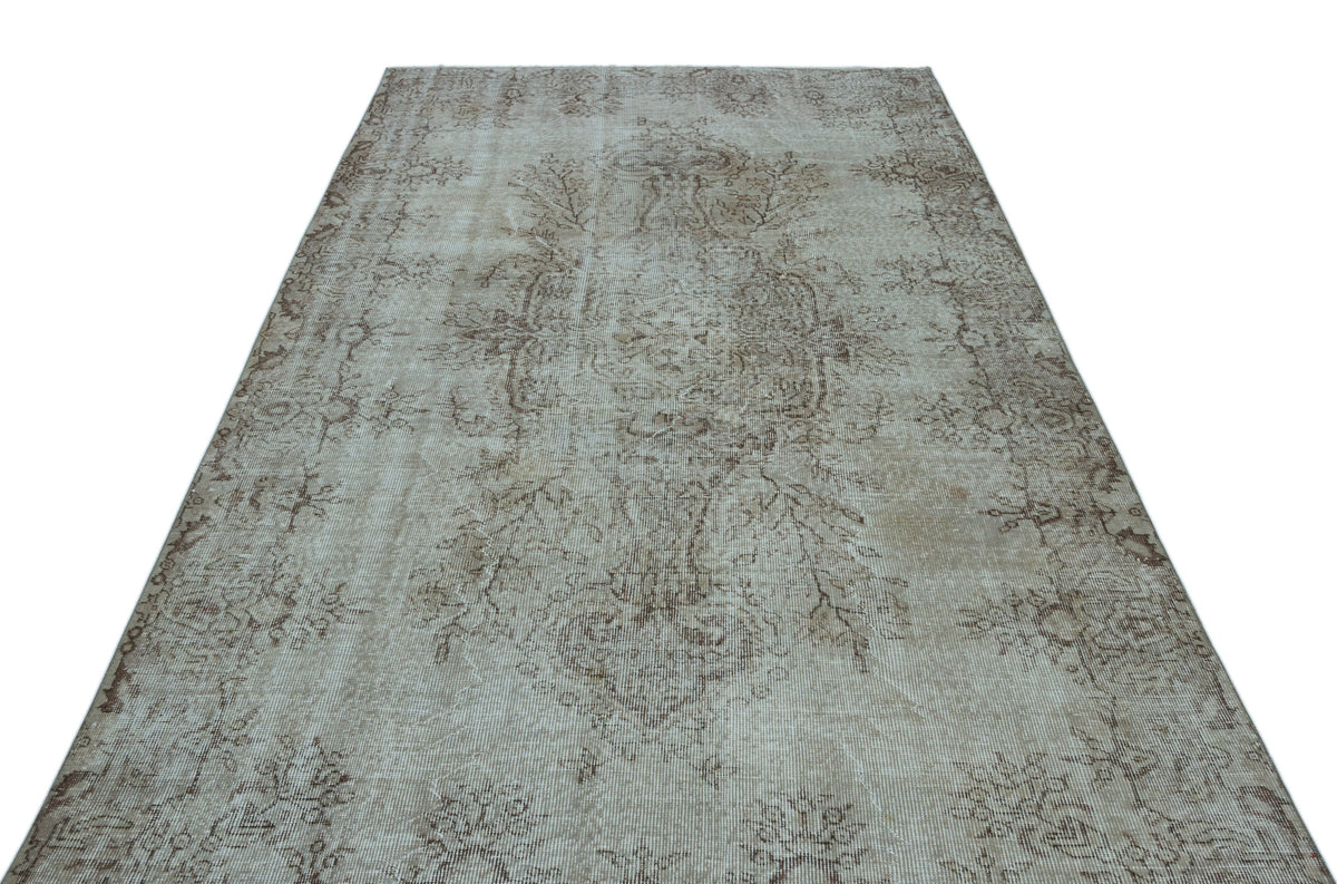 Beige and taupe vintage-style rug with a faded central medallion and intricate floral motifs on a white background.