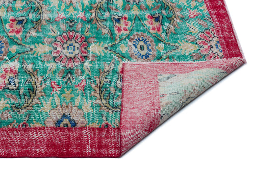 Load image 1 in gallery view. Distressed emerald green rug with a floral medallion pattern, red border, and a corner folded over on a white background.