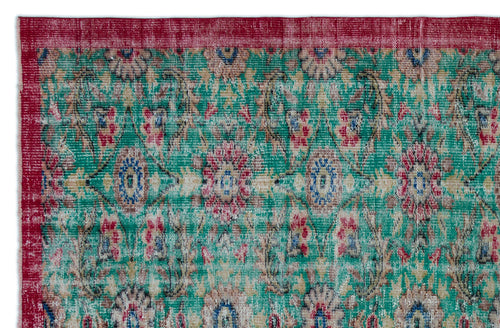 Load image 1 in gallery view. Distressed emerald green rug with a red border and a repeating floral medallion pattern in red, blue, and beige.