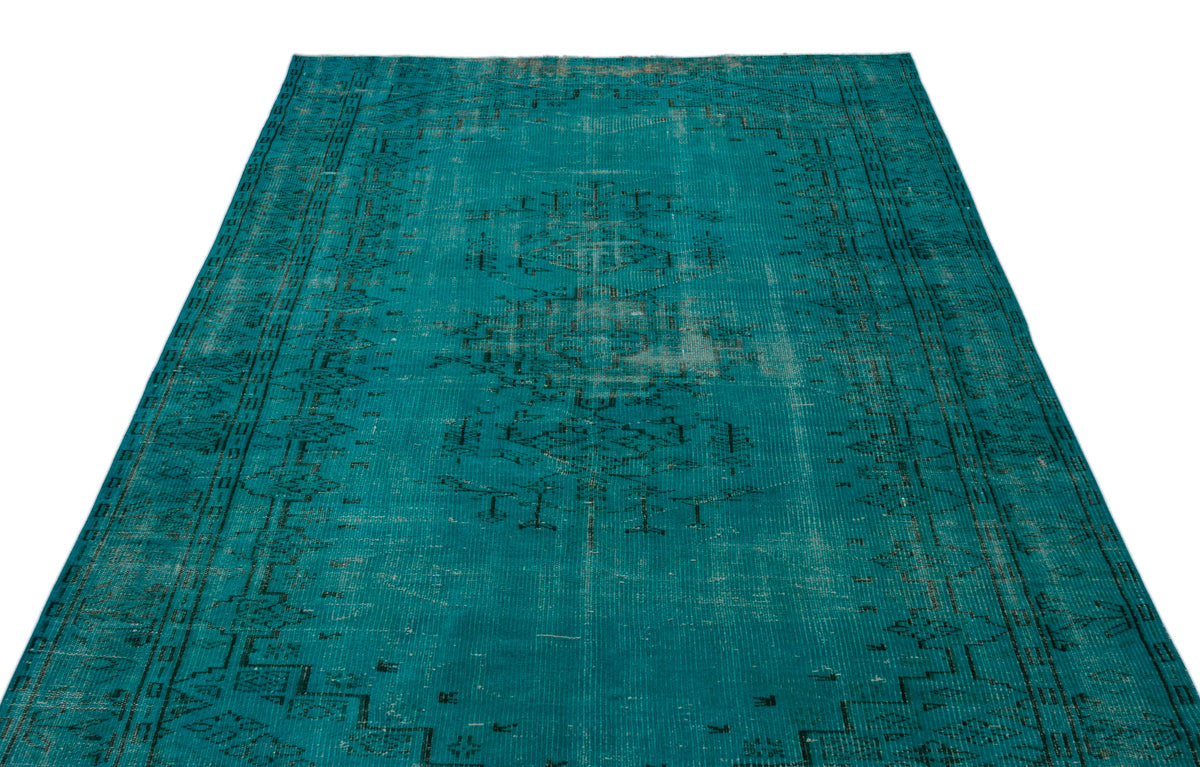Teal vintage-style rug with a distressed black central medallion and geometric border on a white background.