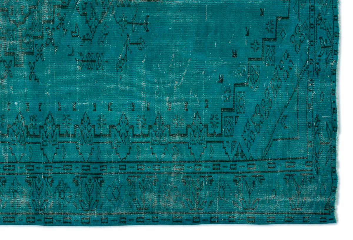 Teal rug with a distressed black geometric border and traditional medallion pattern.