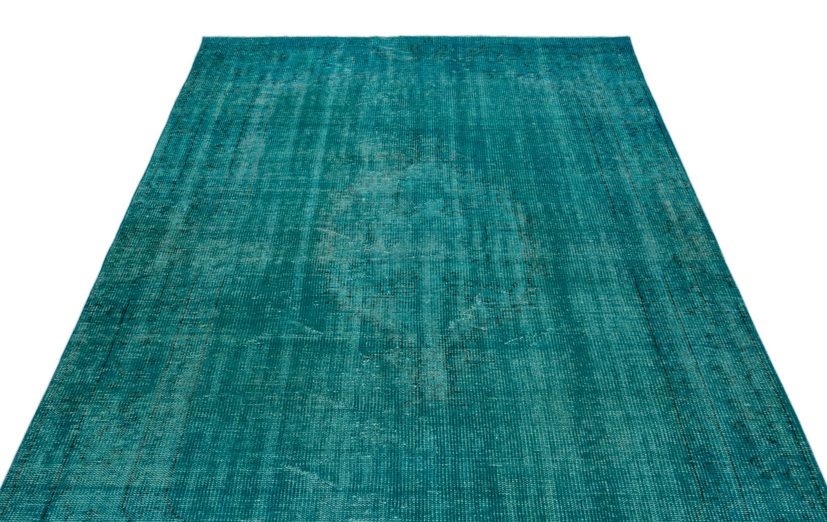 Teal distressed area rug with a faded central medallion and border pattern on a white background.