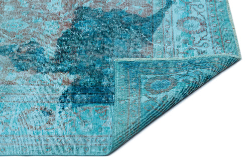 Load image 1 in gallery view. Distressed turquoise and brown vintage-style rug with a faded medallion pattern, shown with a corner folded over.