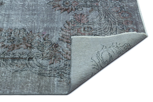 Load image 1 in gallery view. Distressed grey rug with a faded floral medallion pattern and a corner folded over to show the woven backing.