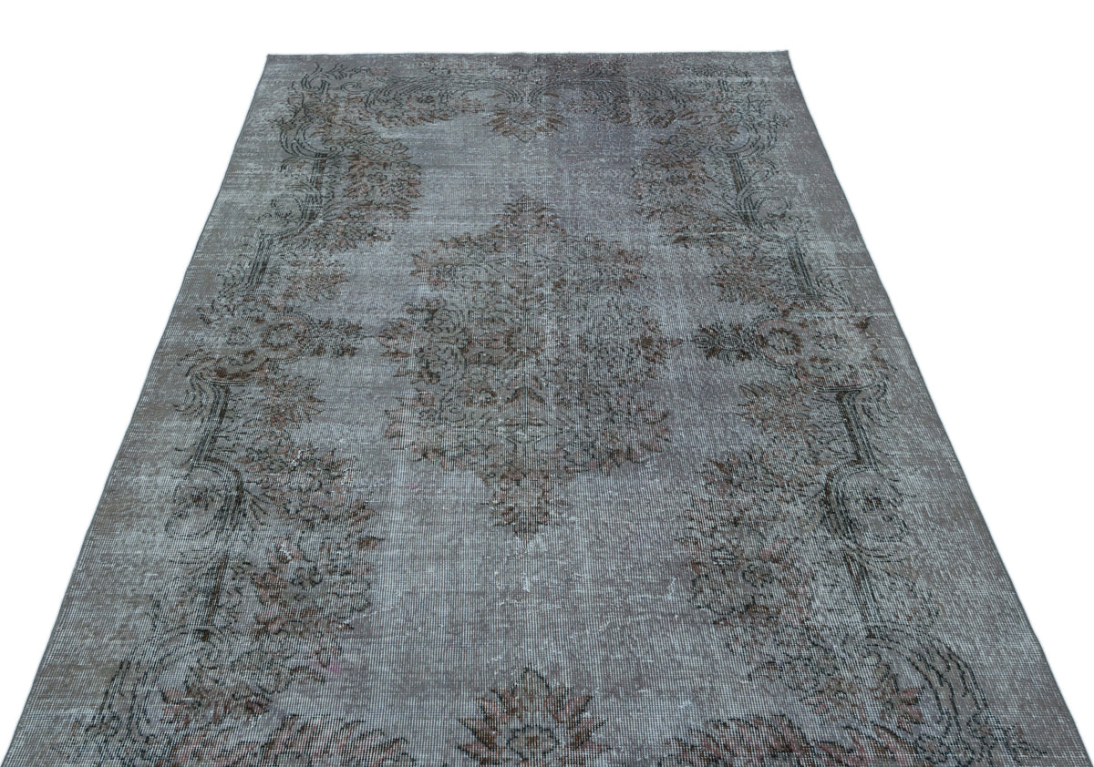 Grey and brown distressed vintage-style rug with a central floral medallion and ornate border on a white background.