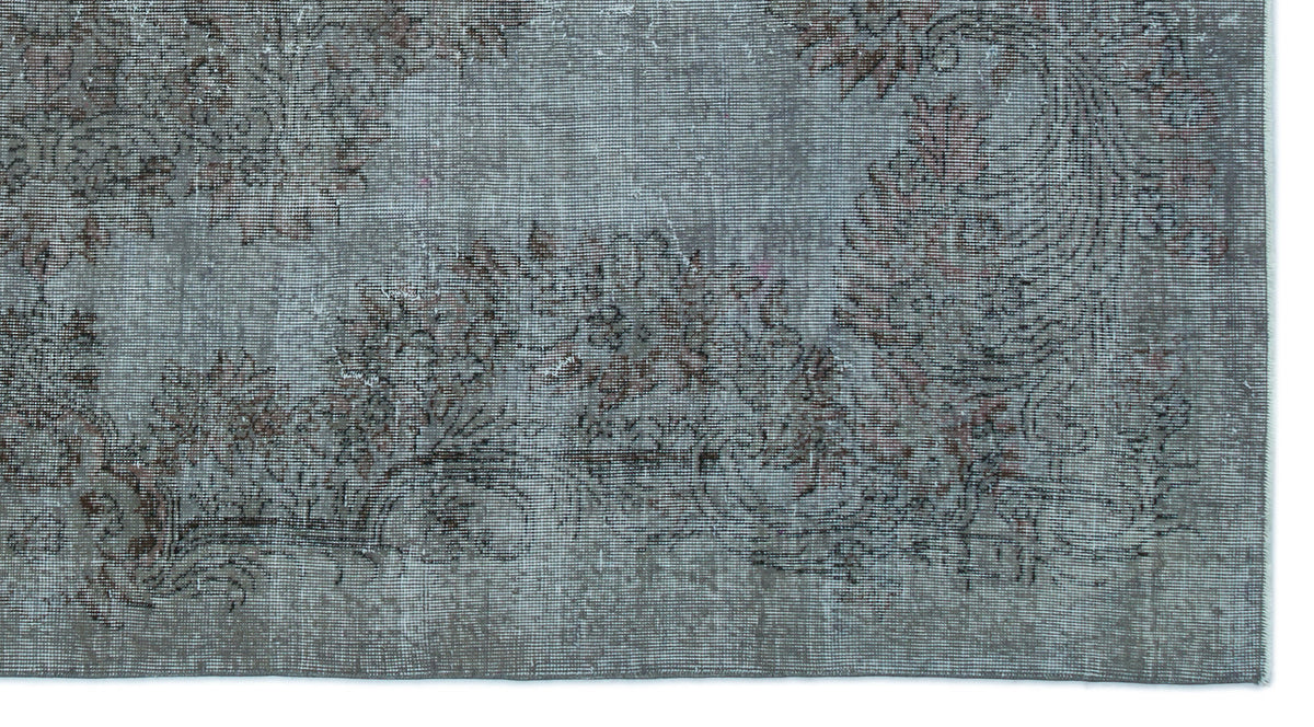 Distressed slate blue rug with a faded floral medallion pattern in muted brown and charcoal tones.