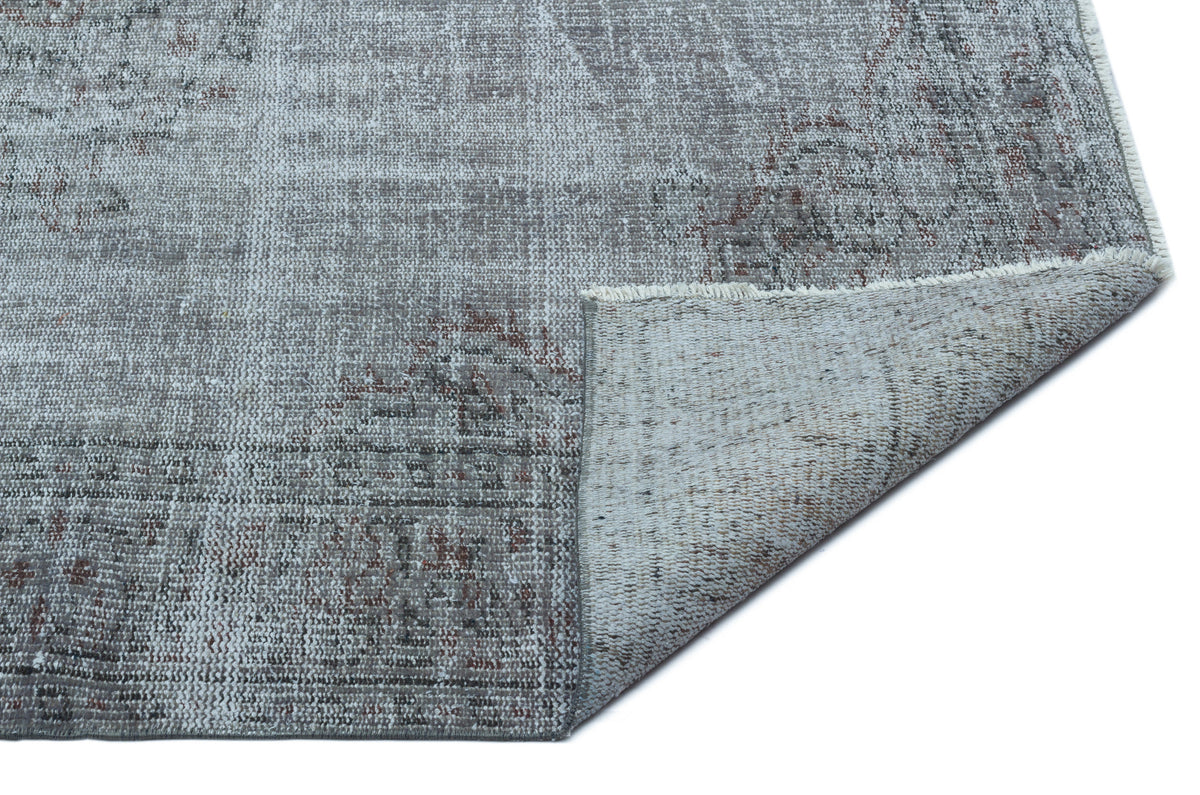 Grey and taupe distressed vintage-style rug with a faded traditional pattern, shown with a corner folded over.