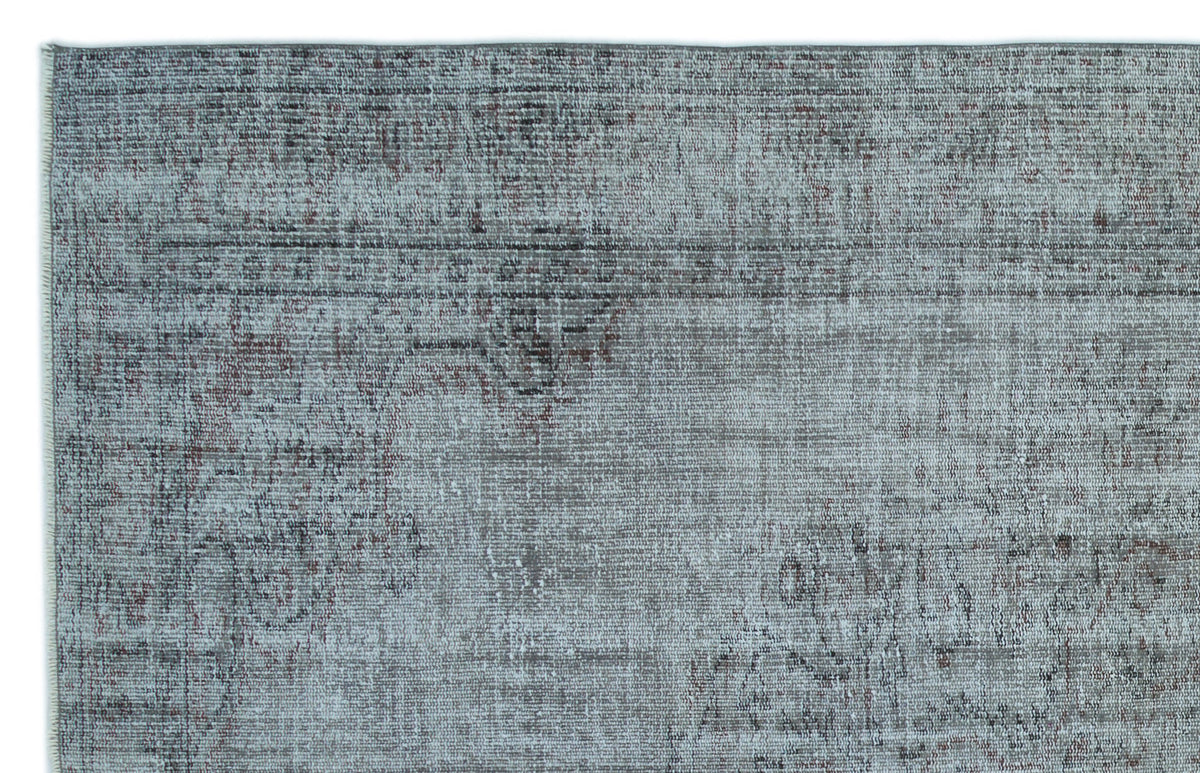 Blue-grey distressed rug with a faded, traditional medallion pattern and dark charcoal accents.