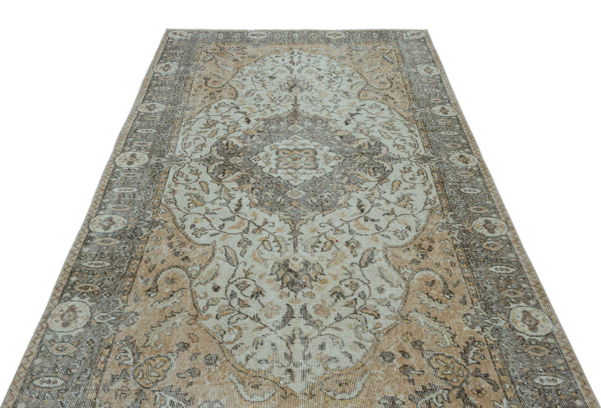 Distressed beige and grey traditional rug with a central floral medallion and ornate border on a white background.