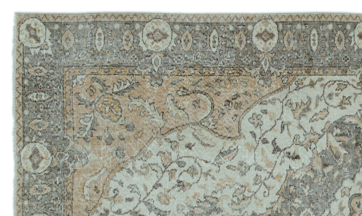 Distressed beige, cream, and charcoal traditional rug with a floral medallion border and intricate botanical motifs.