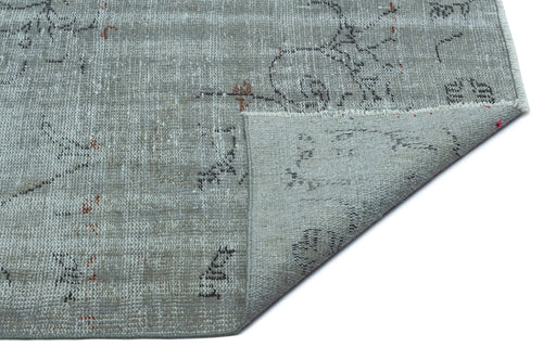Load image 1 in gallery view. Grey distressed rug with a faded floral pattern and small rust-colored accents, shown with a corner folded over.
