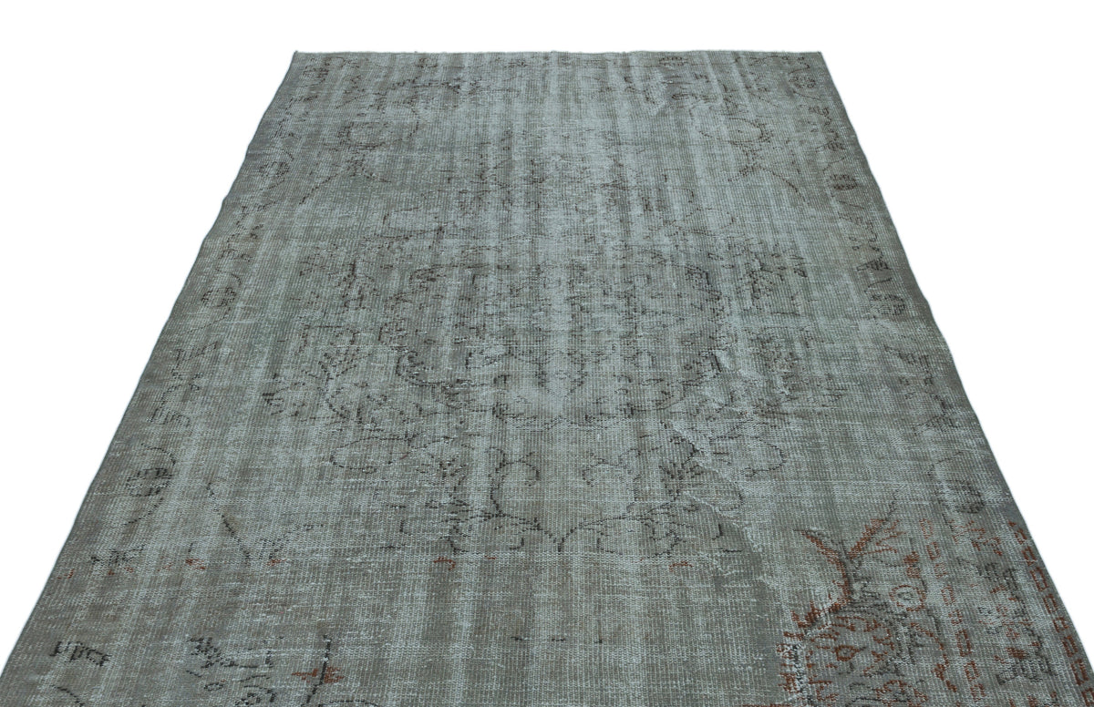 Grey distressed vintage-style rug with a faded central medallion and subtle rust-colored accents on a white background.
