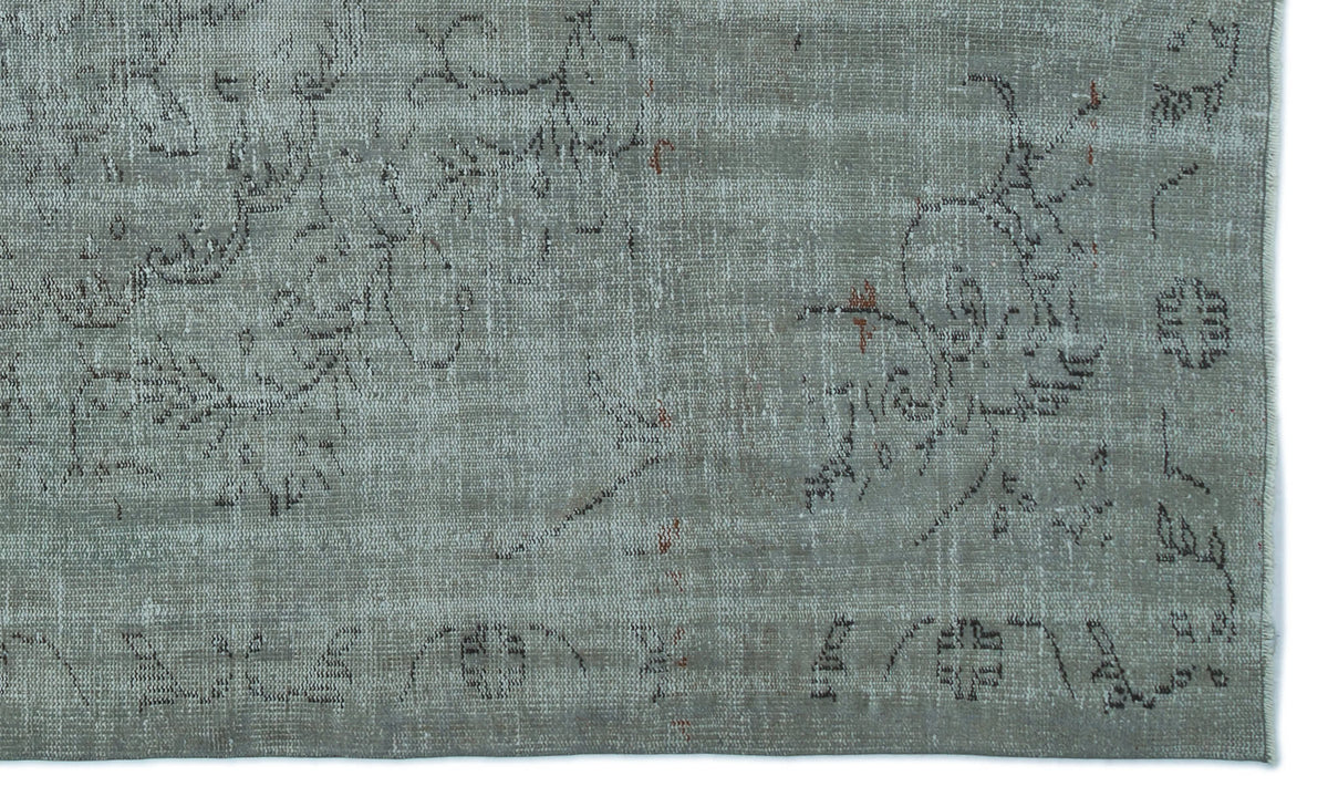 Sage green distressed rug with a faded charcoal floral pattern and subtle rust-colored accents.