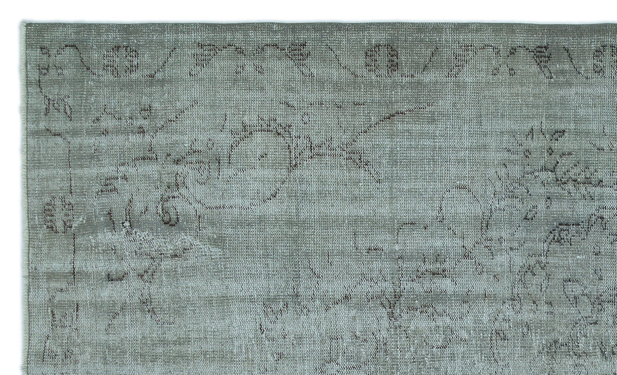 Sage green rug with a distressed, faded traditional floral medallion pattern in dark grey.