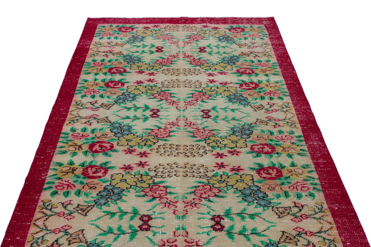 Beige vintage rug with a red border and a repeating floral pattern in red, yellow, blue, and green.