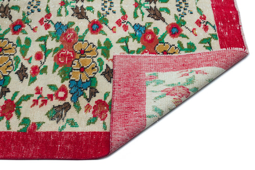Load image 1 in gallery view. Cream rug with a multi-colored floral pattern and a wide red border, shown with a corner folded over on a white background.