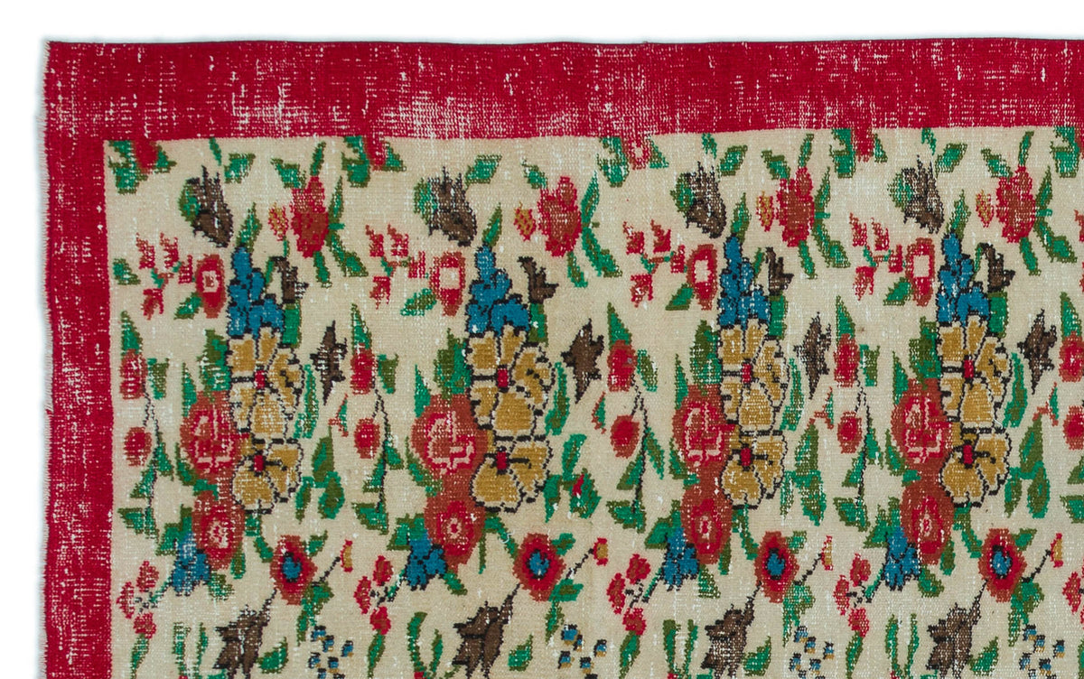 Cream rug with a distressed red border and a repeating floral pattern in red, green, blue, and yellow.