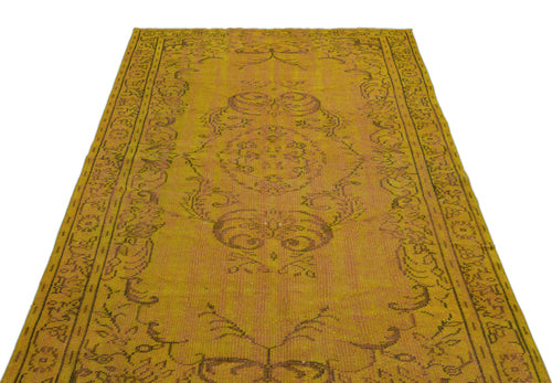 Load image 1 in gallery view. Mustard yellow vintage-style rug with a distressed central medallion and ornate border pattern on a white background.