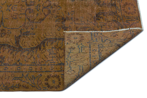 Load image 1 in gallery view. Distressed brown and blue vintage-style rug with a floral medallion pattern, shown with a corner folded over.