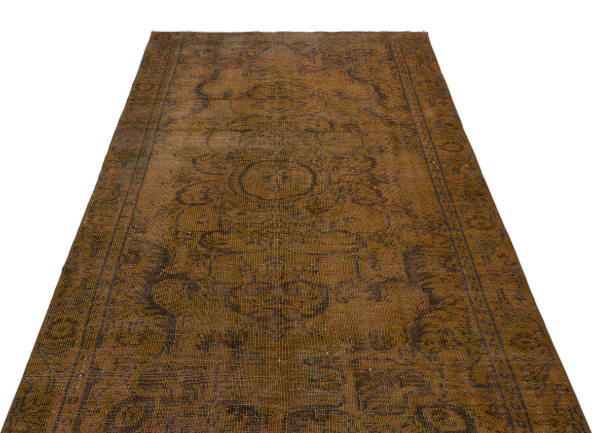 Distressed brown vintage-style rug with a faded dark blue central medallion and ornate border pattern.