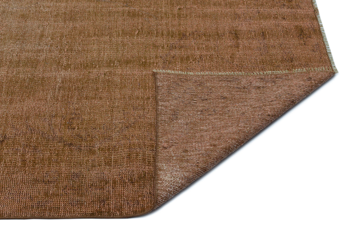 Solid rust-brown distressed rug with a folded corner revealing the textured underside on a white background.