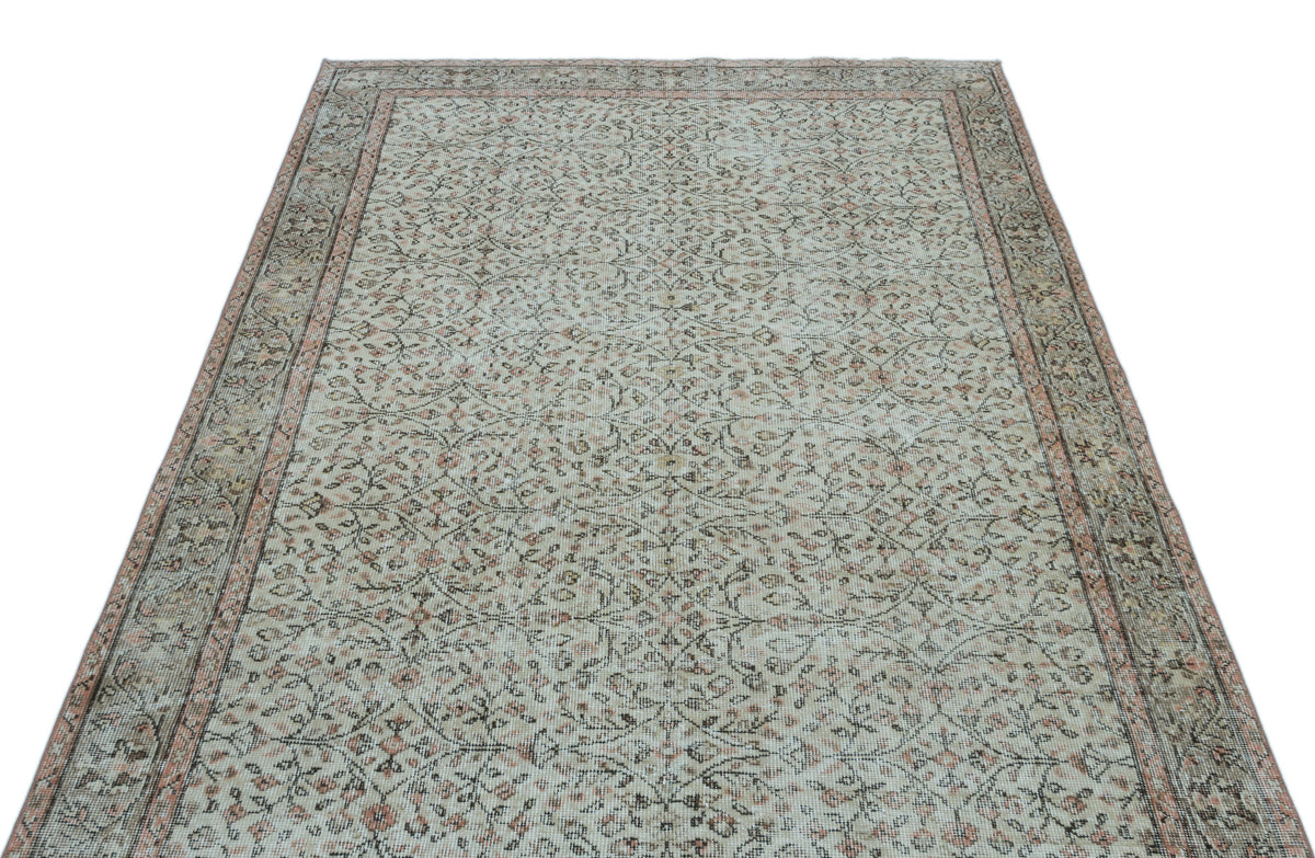 Distressed beige and muted pink rug with an all-over floral vine pattern and a decorative border.