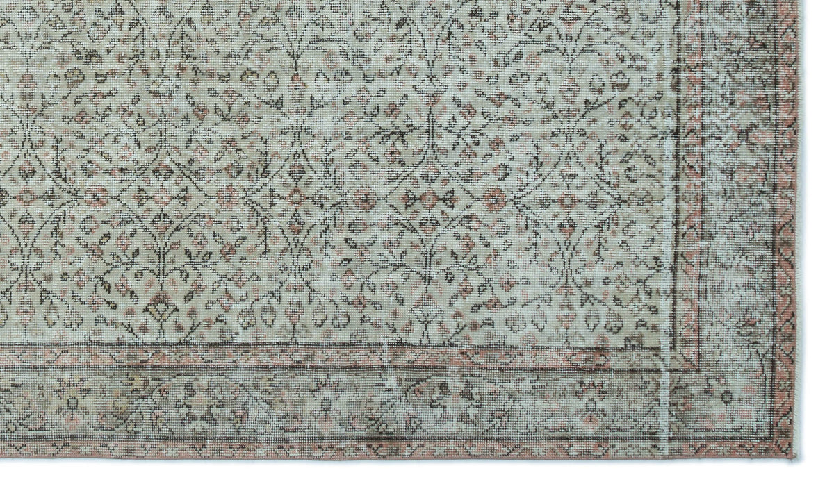 Distressed beige and grey rug with a faded floral trellis pattern and a muted terracotta border.