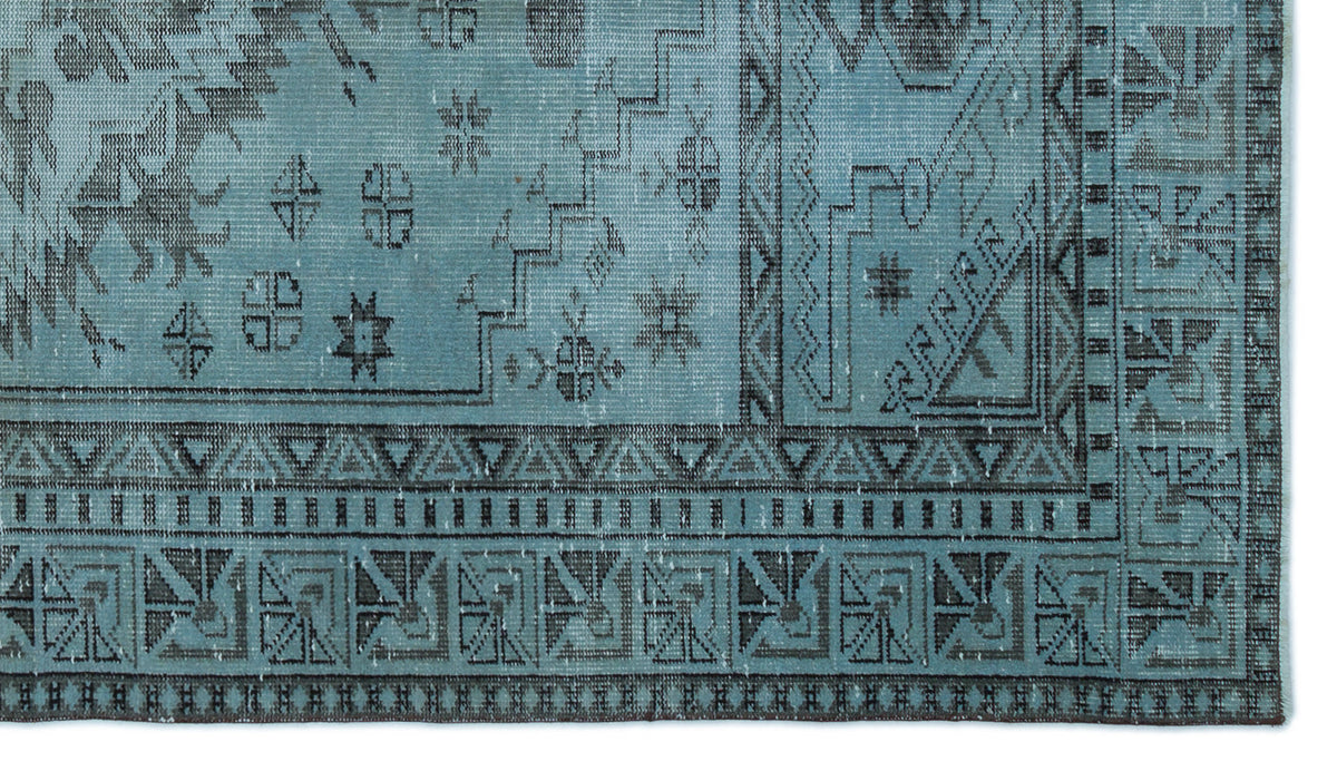 Distressed blue and charcoal rug with a geometric border and traditional tribal motifs.