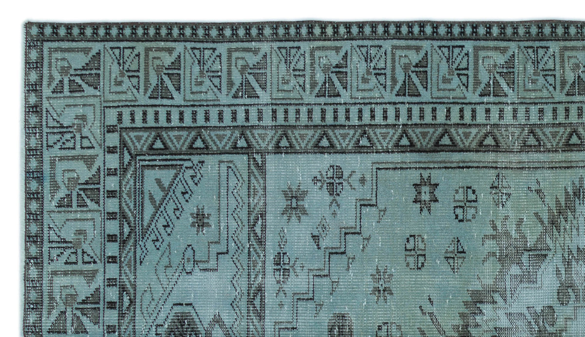 Teal and charcoal rug with a distressed geometric border and scattered tribal motifs.