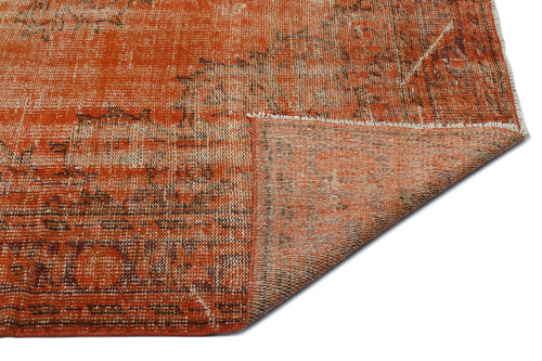 Load image 1 in gallery view. Burnt orange and cream distressed vintage-style rug with a folded corner revealing the woven backing.