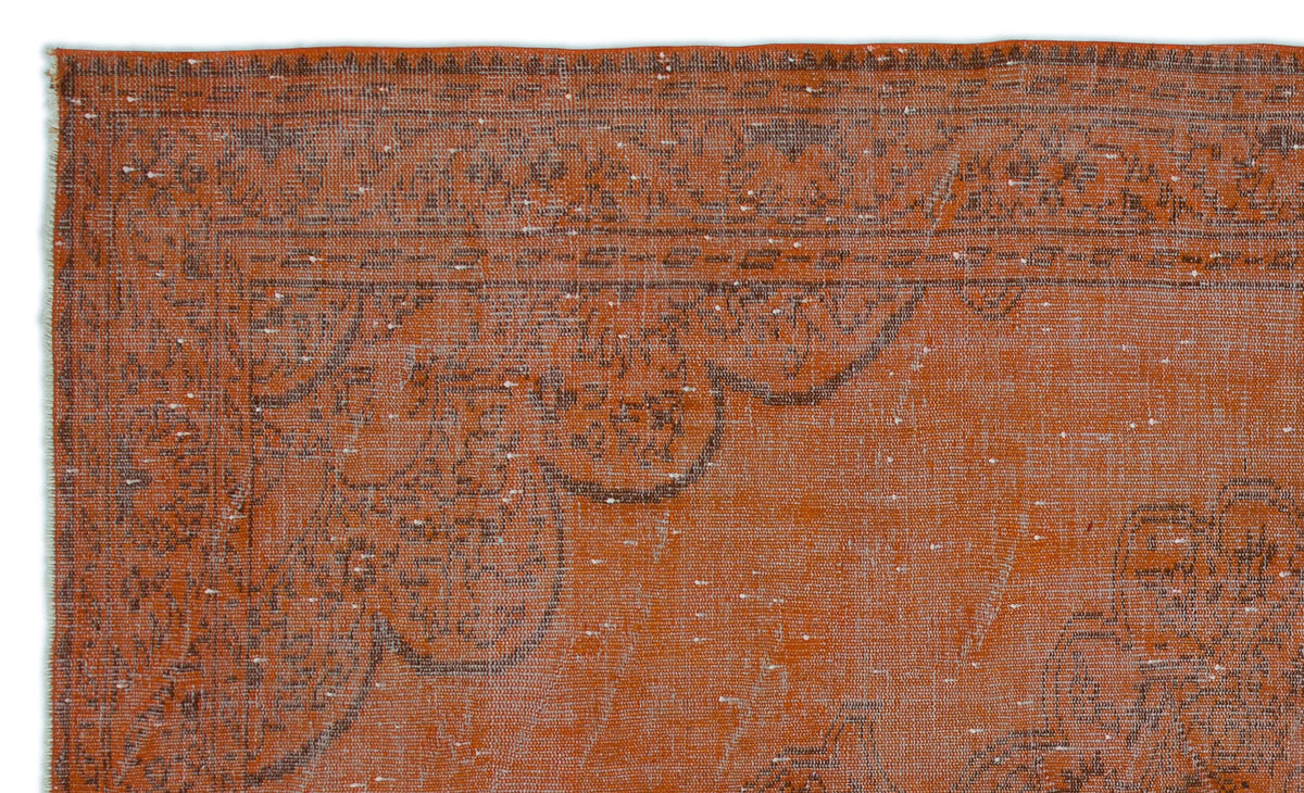 Burnt orange vintage-style rug with a distressed dark brown floral medallion border and white flecked texture.
