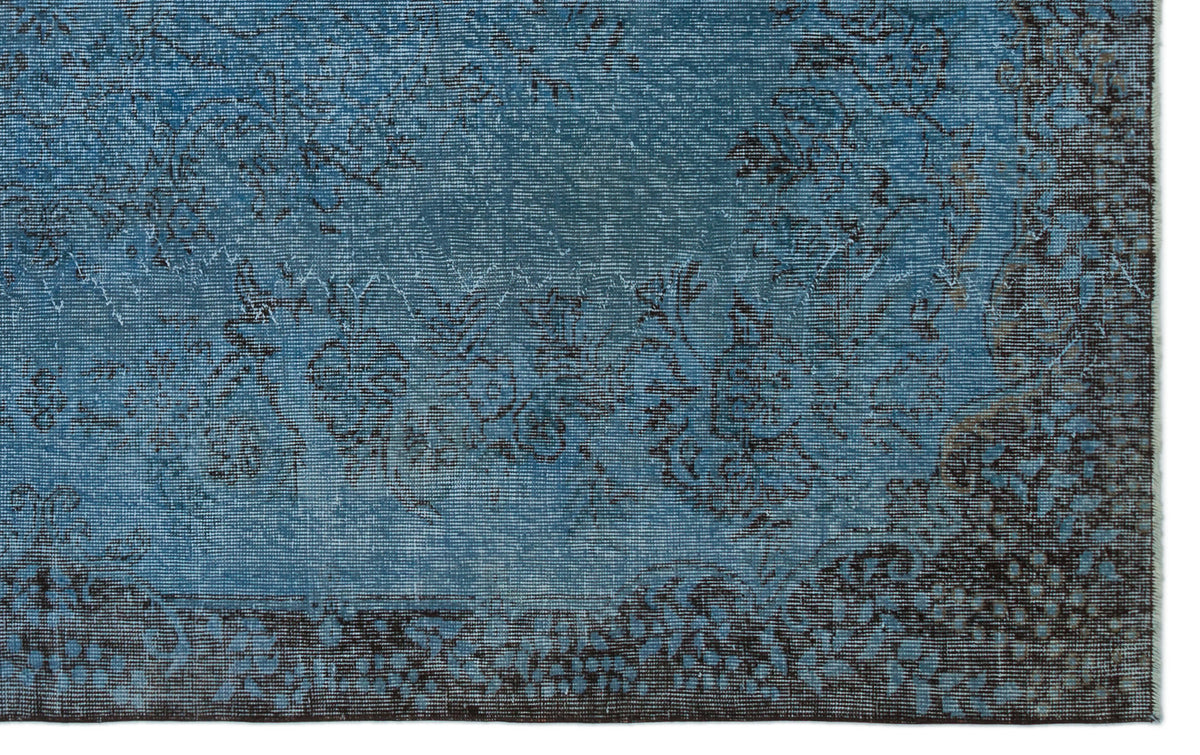 Blue and dark brown distressed rug with a faded floral medallion pattern.
