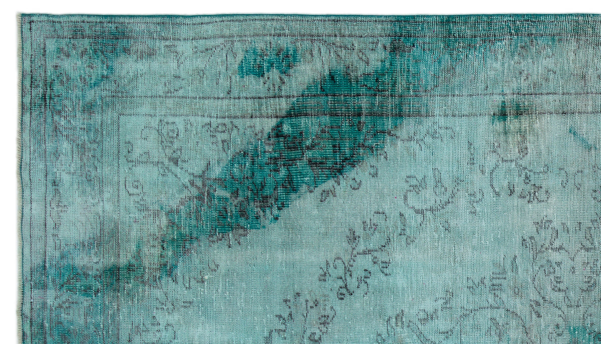 Teal and dark grey distressed rug with a faded floral medallion pattern and a thin border.