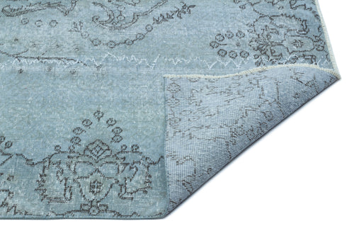 Load image 1 in gallery view. Light blue distressed rug with a dark grey floral medallion pattern and a folded corner showing the backing.
