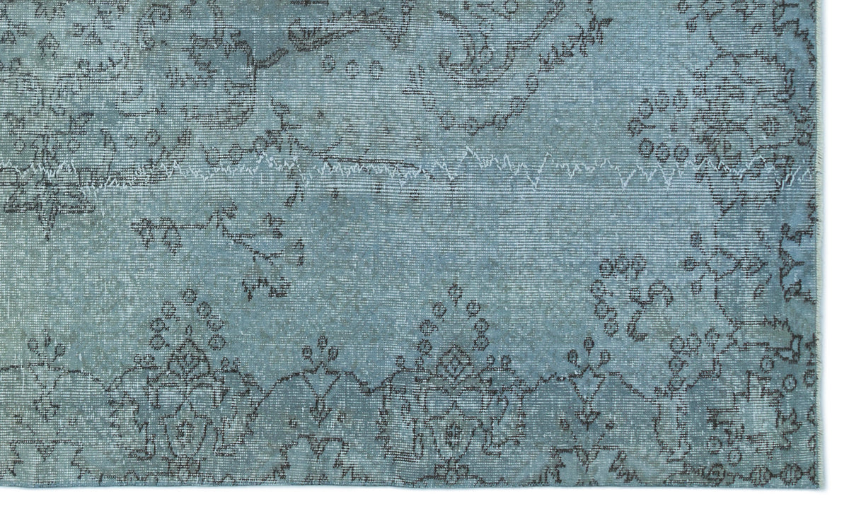 Distressed light blue rug with a dark grey traditional floral medallion pattern and visible stitched seam detail.