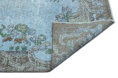 Load image 1 in gallery view. Light blue and brown distressed rug with a floral medallion pattern, shown with a corner folded over.