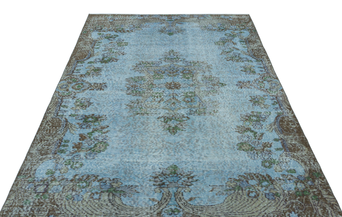Distressed light blue rug with a central floral medallion and brown ornate border on a white background.