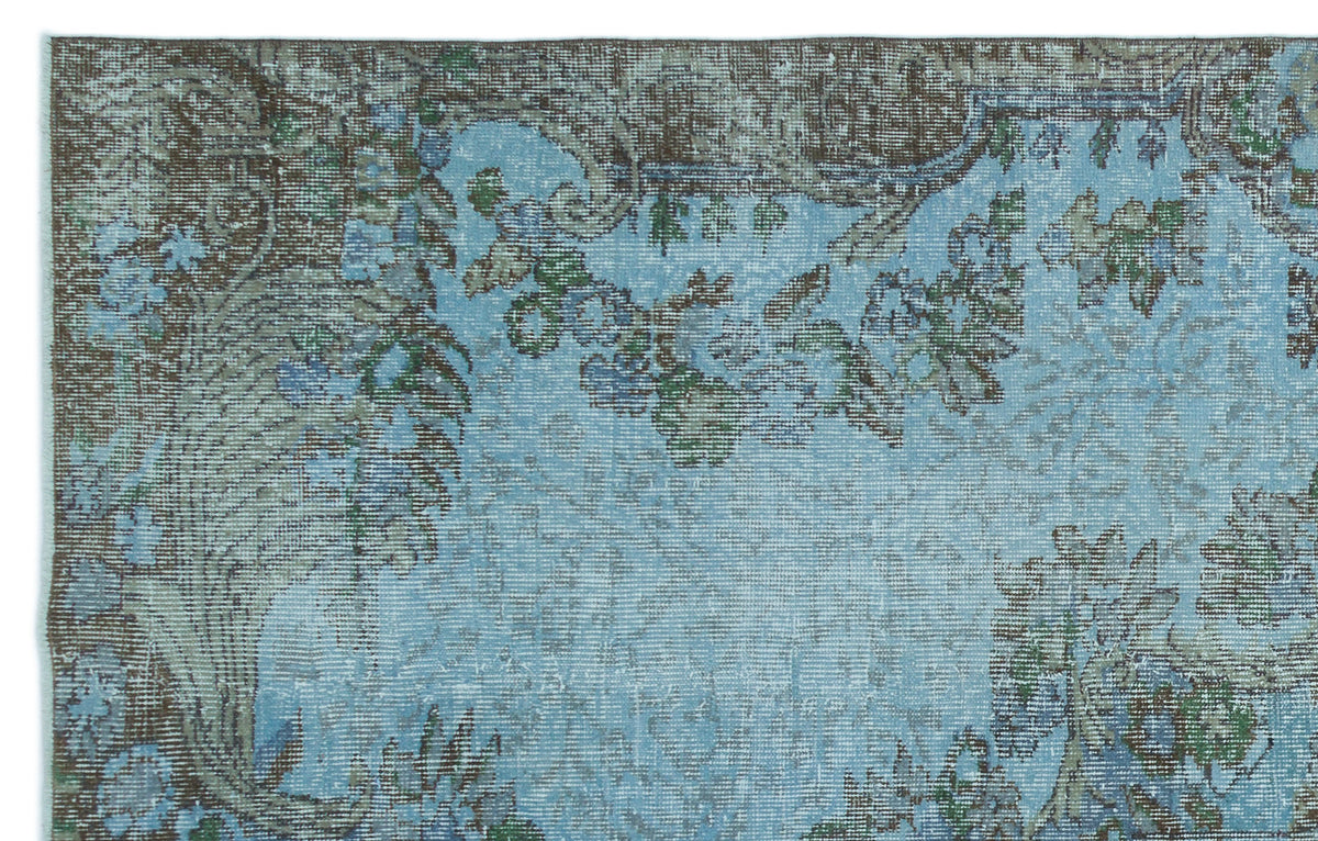 Distressed light blue rug with a dark brown and green floral medallion pattern.