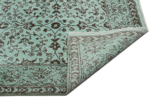 Load image 1 in gallery view. Mint green and brown traditional rug with a floral medallion pattern and a folded corner, isolated on white.
